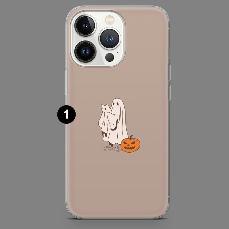 Puede incluir: Una funda de tel&eacute;fono transparente con un fondo marr&oacute;n claro. La funda tiene un dise&ntilde;o de un fantasma sosteniendo un gato y una calabaza de Halloween.