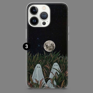 Puede incluir: Una funda transparente para tel&eacute;fono con fondo negro que presenta un cielo nocturno estrellado, una luna llena y dos fantasmas blancos de pie en un campo de hierba verde alta.