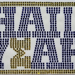 May include: A white background with the words "Hail Yeah" spelled out in blue and gold rhinestones.