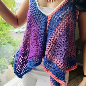 Könnte beinhalten: Ein gehäkeltes Tanktop mit einem Farbverlauf von Rosa, Lila und Blau. Das Oberteil hat eine lockere, fließende Passform und einen V-Ausschnitt. Es ist aus einem leichten Garn gefertigt und hat ein zartes, offenes Webmuster.