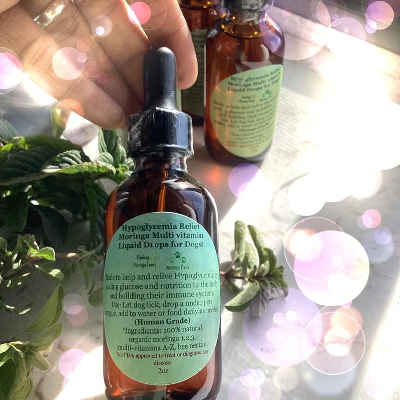 May include: A brown glass bottle with a black dropper, labeled "Hypoglycemia Relief Moringa Multi vitamin Liquid Drops for Dogs!" The label is green and includes text about the product's ingredients and use. The bottle contains 2 oz of liquid.