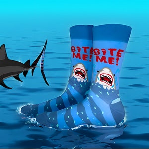 May include: A pair of blue and white striped socks with a shark graphic and the text "Bite Me!" on each sock. The socks are partially submerged in blue water.