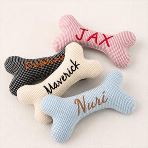 Può includere: Quattro giocattoli di peluche a forma di osso per cani in vari colori e motivi. Ogni osso ha un nome ricamato: Jax, Daphne, Maverick e Nuri. I giocattoli sono rosa, bianco e nero, crema e blu.