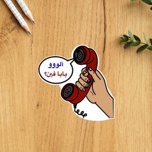 May include: A red rotary phone with a white speech bubble that says "Aloo! Baba Khen?" in Arabic.