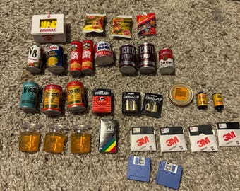 May include: A collection of miniature grocery items and household supplies, including cans of soup, cereal, and batteries, as well as a box of bananas, a pack of film, and floppy disks.