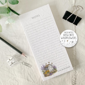 May include: A lined notepad with the word "NOTES" at the top. The bottom features a watercolour illustration of a beehive, flowers, and bees. A circular sticker says "These notes grow into wildflowers."