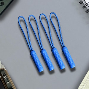 May include: Four blue zipper pulls, each featuring a textured, cylindrical grip attached to a looped cord. The pulls are arranged in a parallel row, showcasing a consistent design with a geometric, diamond-patterned surface on the plastic ends.