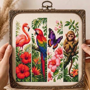 May include: A square cross-stitch embroidery in an ornate bronze-colored frame featuring four vertical panels. The panels depict a pink flamingo with red hibiscus flowers, a colorful macaw parrot, a purple butterfly, and a brown monkey in a tree.
