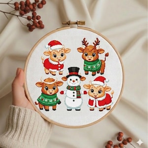 May include: A cross-stitch embroidery hoop featuring a festive design. The design includes five cartoon cows and a snowman, all dressed in holiday attire. The cows wear Santa hats and sweaters. The snowman has a top hat and scarf.