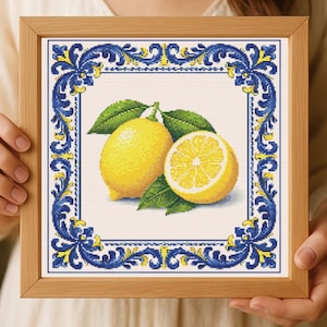 May include: Cross-stitch art of two lemons with green leaves, one whole and one sliced, set against a white background. The artwork is framed with a wooden border and a decorative blue and yellow border.