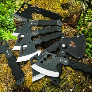 May include: A set of six black throwing axes with silver blades and black handles. The axes are arranged in a fan shape on a mossy surface. Each axe has a hole pattern on the blade and the text "The Ridge" on the handle.