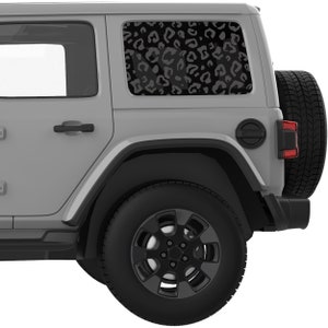May include: A gray Jeep Wrangler with a black leopard print decal on the rear window. The vehicle has black wheels and tires.
