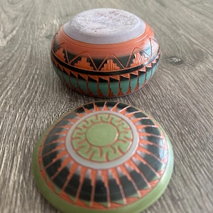 Puede incluir: Un juego de dos cuencos de cerámica nativa americana con intrincados diseños geométricos en tonos de verde, negro, naranja y blanco. Los cuencos están hechos de arcilla y tienen un acabado liso y pulido.