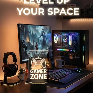 Pode incluir: Uma configuração de jogos com um computador de mesa, monitor, teclado e mouse. Uma placa iluminada com um gráfico de controlador e as palavras "GAMER ZONE" está na mesa. O texto "LEVEL UP YOUR SPACE" está acima.