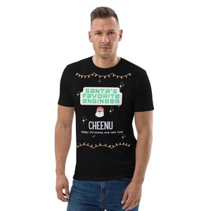 May include: Black t-shirt with a Christmas lights design. The text "Santa's Favorite Engineer" is in green and the name "CHEENU" is in purple. The text "Happy Christmas and New Year" is below the name.