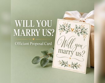 May include: A cream-colored officiant proposal card featuring the text Will you marry us? in elegant script, decorated with green watercolor leaves, small white flowers, and gold heart accents, displayed next to a gift box with a white ribbon.
