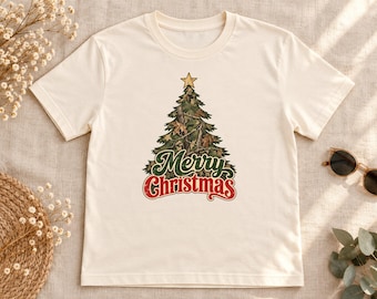May include: A cream-colored short-sleeve t-shirt featuring a graphic of a Christmas tree with a camouflage pattern and a gold star on top. The text Merry Christmas is printed below the tree in green and red stylized lettering.