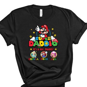 May include: Black t-shirt with a Super Daddie graphic featuring Mario from the Super Mario Bros. video game. The text "It's a me, Daddy!" is below the graphic. The names Sophia, Noah, and Ava are below the text.