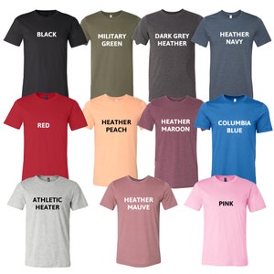 Puede incluir: Una selecci&oacute;n de camisetas de varios colores, incluyendo negro, rojo, rosa, azul, verde, gris y melocot&oacute;n. Cada camiseta tiene un color y un texto diferente impreso en la parte delantera.