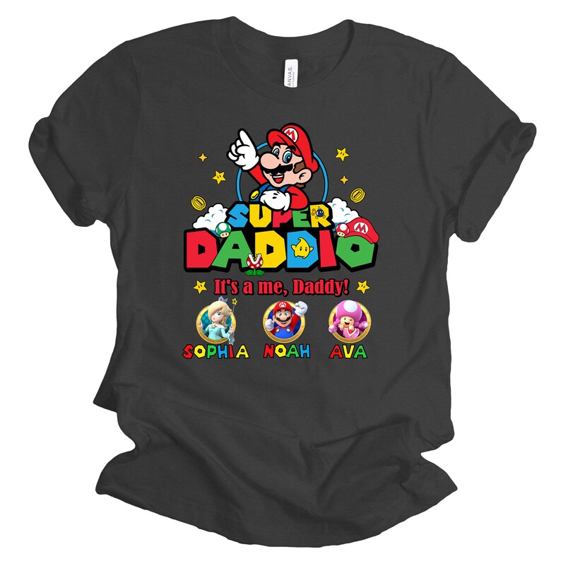 May include: A dark grey t-shirt with a Super Daddi design featuring a cartoon Mario character. The text "It's a me, Daddy!" is printed below the character. Three smaller cartoon characters are printed below the text, with the names Sophia, Noah, and Ava printed below each character.