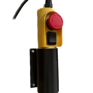 Może przedstawiać: Żółto-czarny elektryczny przełącznik sterujący z czerwonym przyciskiem i czarnym przełącznikiem dźwigniowym. Przełącznik jest zamontowany na czarnym wsporniku.