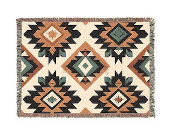 May include: A woven throw blanket with a geometric pattern in shades of brown, black, white, and green. The pattern features repeating diamond and star shapes.