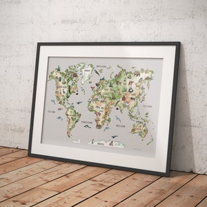 Op de afbeelding: Ingelijste wereldkaart kunstprint met een aquarel illustratie van de continenten en oceanen. De kaart bevat dier illustraties en labels. De print zit in een zwart frame en leunt tegen een witte muur en een houten vloer.
