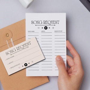 May include: Two white cards with the text "SONG REQUEST" printed on them. The cards have lines for writing down song requests, artist, and who requested the song. The cards are on a brown envelope.