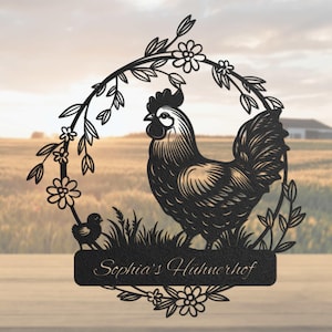 Könnte beinhalten: Schwarze Metallsilhouette eines Hahns und eines Küken in einem Blumenkranz mit dem Text "Sophia's Hühnerhof" auf einem Schild darunter.