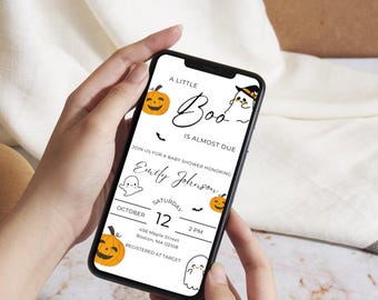 May include: A mobile phone screen shows a Halloween-themed baby shower invitation. The design includes orange pumpkins, ghosts, and the phrase "A Little Boo Is Almost Due." The event is on October 12th at 2 PM.