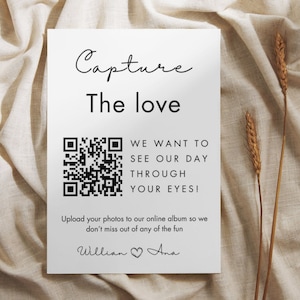 以下が含まれることがあります： 「Capture The Love」とQRコードが書かれた白いカード。QRコードの下のテキストは「We want to see our day through your eyes! Upload your photos to our online album so we don't miss out of any of the fun. Willian Ana」です。