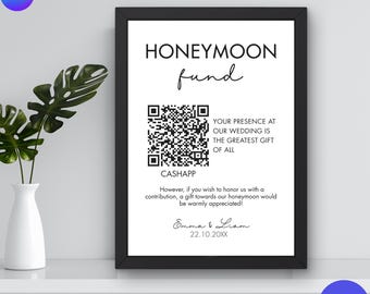 May include: A black framed sign with the words "HONEYMOON fund" in a handwritten font. The sign includes a QR code and text that reads "YOUR PRESENCE AT OUR WEDDING IS THE GREATEST GIFT OF ALL".