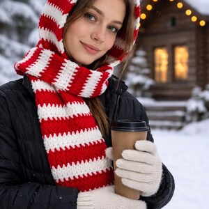 May include: A white ceramic mug with a black handle and the text "But First, Coffee" in a bold, black font. The mug is set against a blurred background, suggesting a cozy setting.