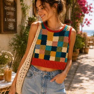 May include: A colorful, sleeveless crochet top with a patchwork design in shades of blue, green, yellow, and red. The top is paired with light blue jeans and a cream-colored tote bag. The image also shows a sign that says "Good Vibes Coffee & Sunshine."