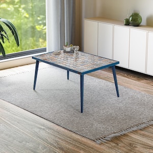 Può includere: Un tavolino da caffè blu con un piano in piastrelle con motivi. Il tavolo ha una base in legno chiaro e si trova su un tappeto grigio.