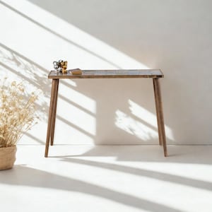 Peut inclure: Une console en bois avec un dessus en mosaïque. La table a quatre pieds inclinés et est ornée d'objets décoratifs. La table est placée contre un mur blanc avec des ombres.
