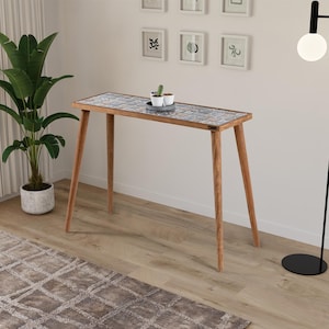 Può includere: Un tavolo consolle in legno con piano piastrellato, con un mix di motivi blu, grigi e bianchi. Il tavolo ha quattro gambe angolate ed è adornato con piccole piante in vaso. Il tavolo è lungo 122 cm.