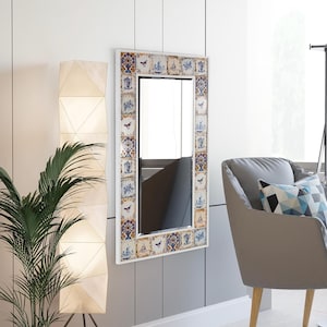 May include: A white framed mirror with a decorative border of blue and white Delft tiles. The tiles feature floral patterns, birds, and windmills.