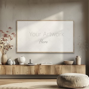 Könnte beinhalten: Eine Holz-TV-Konsole mit einem gerahmten Leinwanddruck, auf dem "Your Artwork Here" steht. Die Konsole ist mit Trockenblumen, Vasen und einer Schale dekoriert. Vor der Konsole steht ein großer, runder, hellbrauner Hocker.