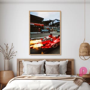 May include: A framed print of a Formula 1 race car in action. The red car with the "Marlboro" logo is on the track, with flames coming from the exhaust. The background shows the pit lane and spectators.