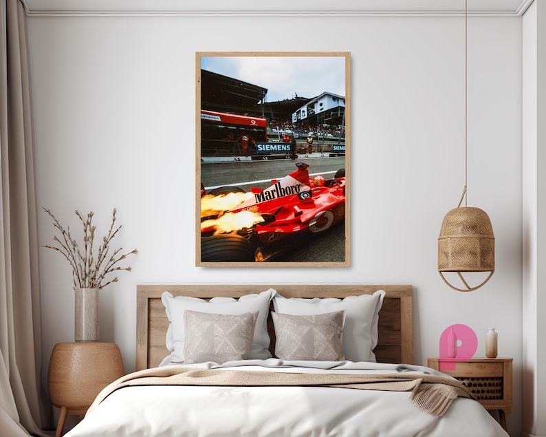 May include: A framed print of a Formula 1 race car in action. The red car with the "Marlboro" logo is on the track, with flames coming from the exhaust. The background shows the pit lane and spectators.