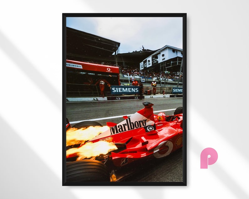 May include: Framed print of a red Formula 1 race car with the Marlboro logo, flames emitting from the exhaust. The car is on a racetrack with the Siemens logo visible in the background.