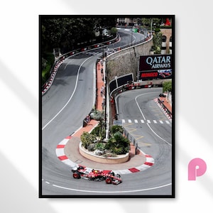 May include: A framed print of a Formula 1 race in Monaco. The image shows a red and white race car on a winding track with a large Qatar Airways sign. The track is surrounded by barriers and spectators.
