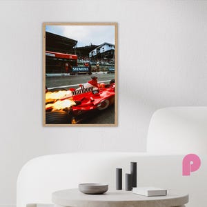 May include: A framed print of a red Formula 1 race car with the Marlboro logo, flames erupting from the exhaust. The image captures the car in motion on a racetrack, with a backdrop of buildings and spectators. The print is in a wooden frame.