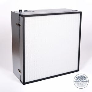 Puede incluir: Una caja de metal plateada con un filtro blanco en su interior. La caja tiene un marco negro alrededor del filtro y dos cierres plateados en el lateral.