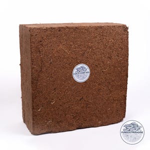 May include: A brown brick of compressed coconut coir, a natural growing medium for mushrooms. The brick has a white label that reads "Coco Coir 5KG" and a white sticker with a mushroom illustration and the text "Fungus Paradise".