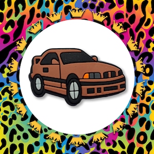 May include: A brown toy car with a black windscreen and black wheels. The car has a rounded front end and a slightly raised rear end.