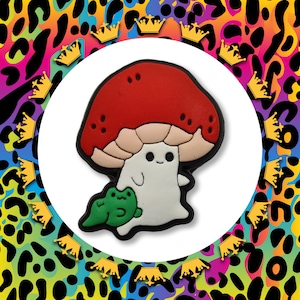 May include: A red and white mushroom with a smiling face and a small green frog sitting on its stem. The mushroom is a cartoon character with a friendly expression.