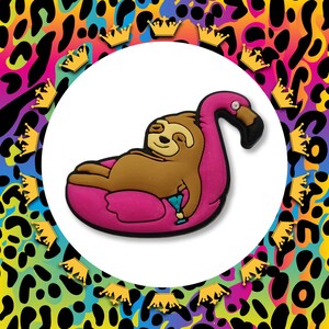 May include: A brown sloth wearing a pink flamingo float. The sloth is smiling and has its arms outstretched. The flamingo float is pink and has a white beak.