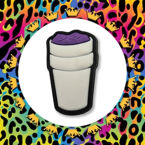 May include: A purple and white polystyrene cup with a black outline. The cup is filled with a purple liquid and has a white lid.